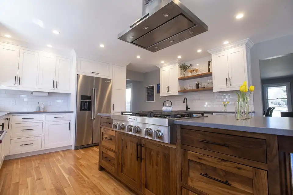 Kitchen remodeling Montpelier VT area project in Stowe: walnut-stained island with gas range, ceiling-mounted stainless hood, white cabinets and open wood shelves
