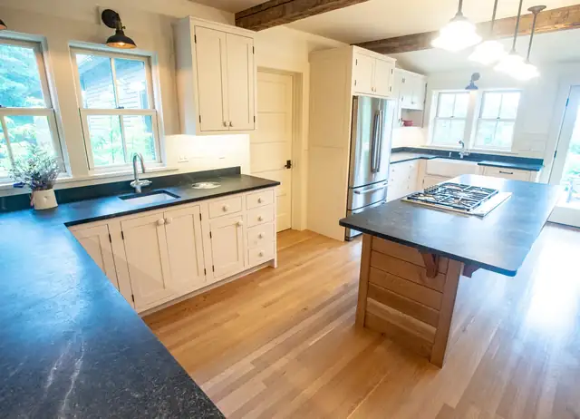 Montpelier, VT kitchen with cream cabinets, soapstone counters, a wood island and reclaimed ceiling beams