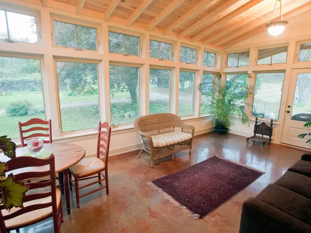 Sunroom addition with a wall of windows, wood ceiling, stained concrete floor and dining table
