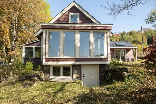 Rear addition with tall windows and walkout lower level on a Vermont home in fall