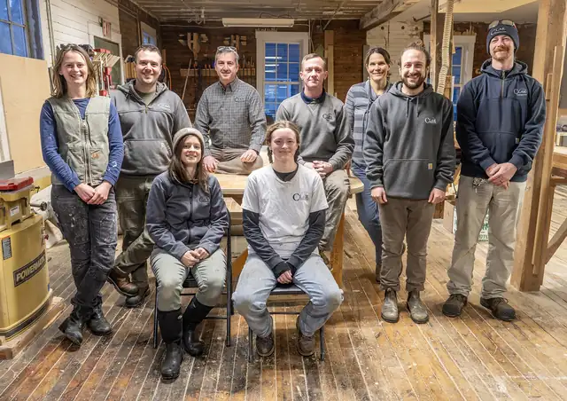 The Clar Construction team gathered in their wood-floored millwork shop
